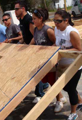 Students raising a wall on a new house